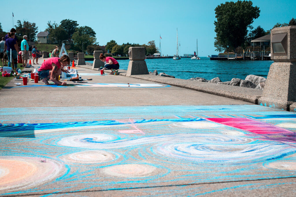 Children doing sidewalk art with chalk by the ocean